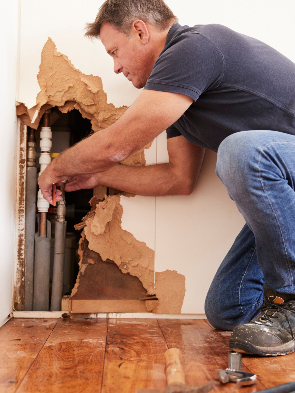 Condo Association Claim Scenario plumber fixing a leak in a shared condo wall